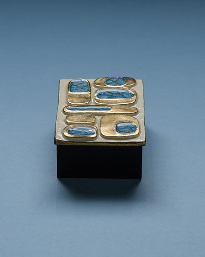 Boîte en céramique émaillée de Mithé Espelt réalisée dans les années 1960. Couvercle décoré de cabochons en verre bleu incrustés dans des alvéoles dorées à l'émail craquelé, sur fond ivoire. Base en bois peint noir.
Très bel état.