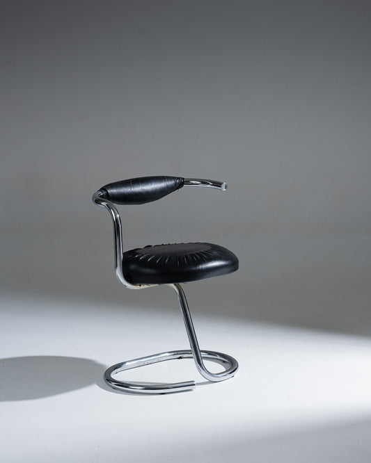 Chaise modèle "Cobra" du designer italien Giotto Stoppino (1926–2011). Structure en acier tubulaire chromé, réalisée d’une seule pièce intégrant la base, l’assise et le dossier. Revêtement en simili cuir noir déhoussable, avec étiquette d’origine sous l’assise.&nbsp;
Bel état général, à noter de légères traces d'usage : craquelures visibles sur le dossier (voir photos).&nbsp;