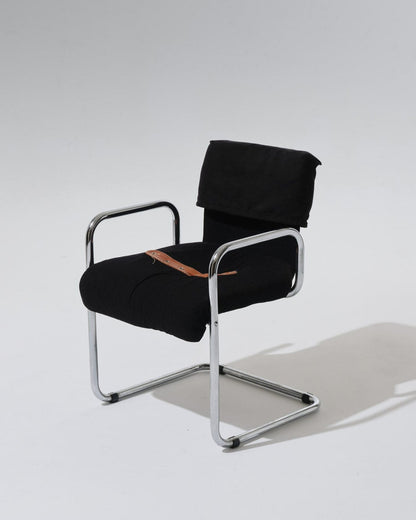 Chaise au design typique des créations de Guido Faleschini pour Mariani dans les années 1970. Structure en acier tubulaire chromé, assise et dossier généreusement rembourrés et recouverts d'un velours noir profond. Une sangle en cuir cognac, fixée par oeillets métalliques, souligne la ligne du siège.
Superbe état.