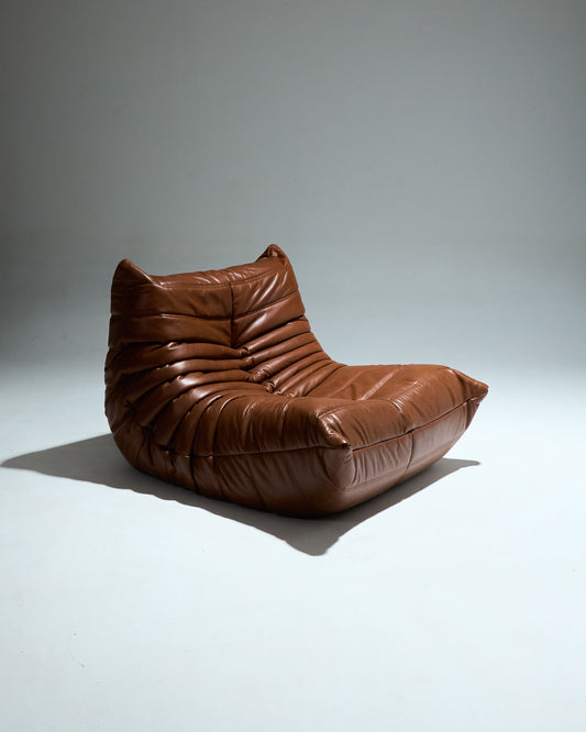 Fauteuil TOGO du designer Michel Ducaroy (1925-2009) pour Ligne Roset dans les années 1970. Grand classique du design cette chauffeuse entièrement en mousse est recouverte d'une housse en cuir brun d'origine. Pièce étiqueté.
Très bon état général. À noter légère décoloration du cuir à certains endroits (voir photo).