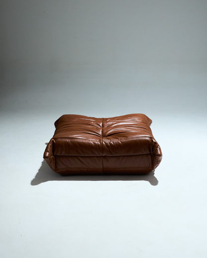 Ottoman TOGO du designer Michel Ducaroy (1925-2009) pour Ligne Roset dans les années 1970. Grand classique du design cet ottoman entièrement en mousse est recouvert d'une housse en cuir brun d'origine. Pièce étiquetée.
Très bon état général. À noter, une légère décoloration du cuir à certains endroits (voir photo).