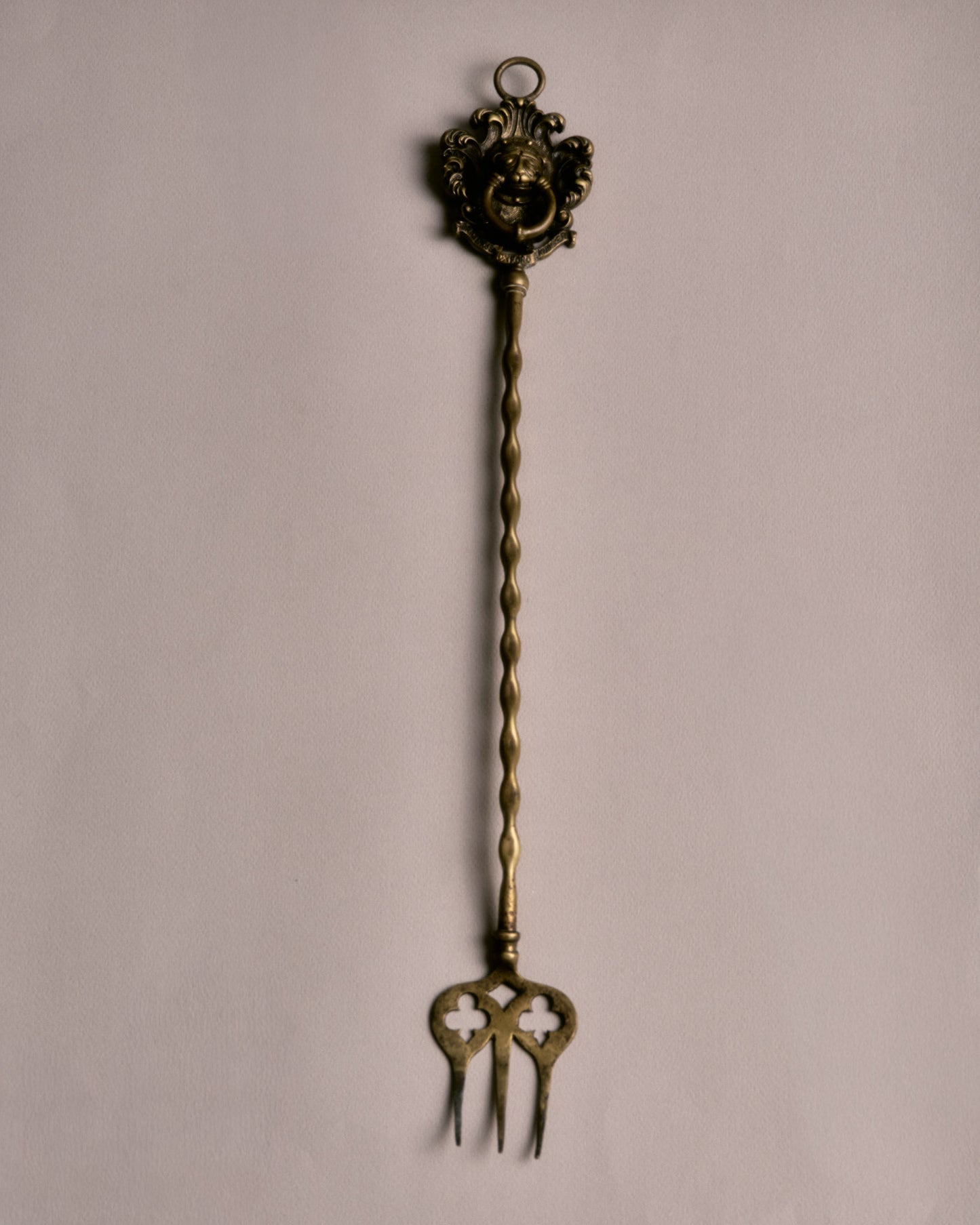 Fourche à braise en laiton doré, dotée d'un manche torsadé et d'un trident ajouré à motif de trèfles. La base est ornée d'un mascaron baroque entouré de volutes et de feuillages stylisés.
Bon état général, légère patine conforme à l'âge et à l'usage.
