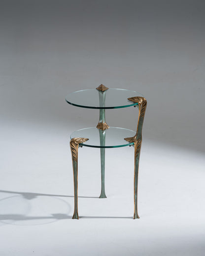 Guéridon tripode en laiton et en verre. Deux plateaux de tailles différentes glissés dans les pieds Décors des montants vert et or en forme de feuilles d'acanthe Art Déco. Se rapprochant des travaux des années 1970. Belle patine.&nbsp;