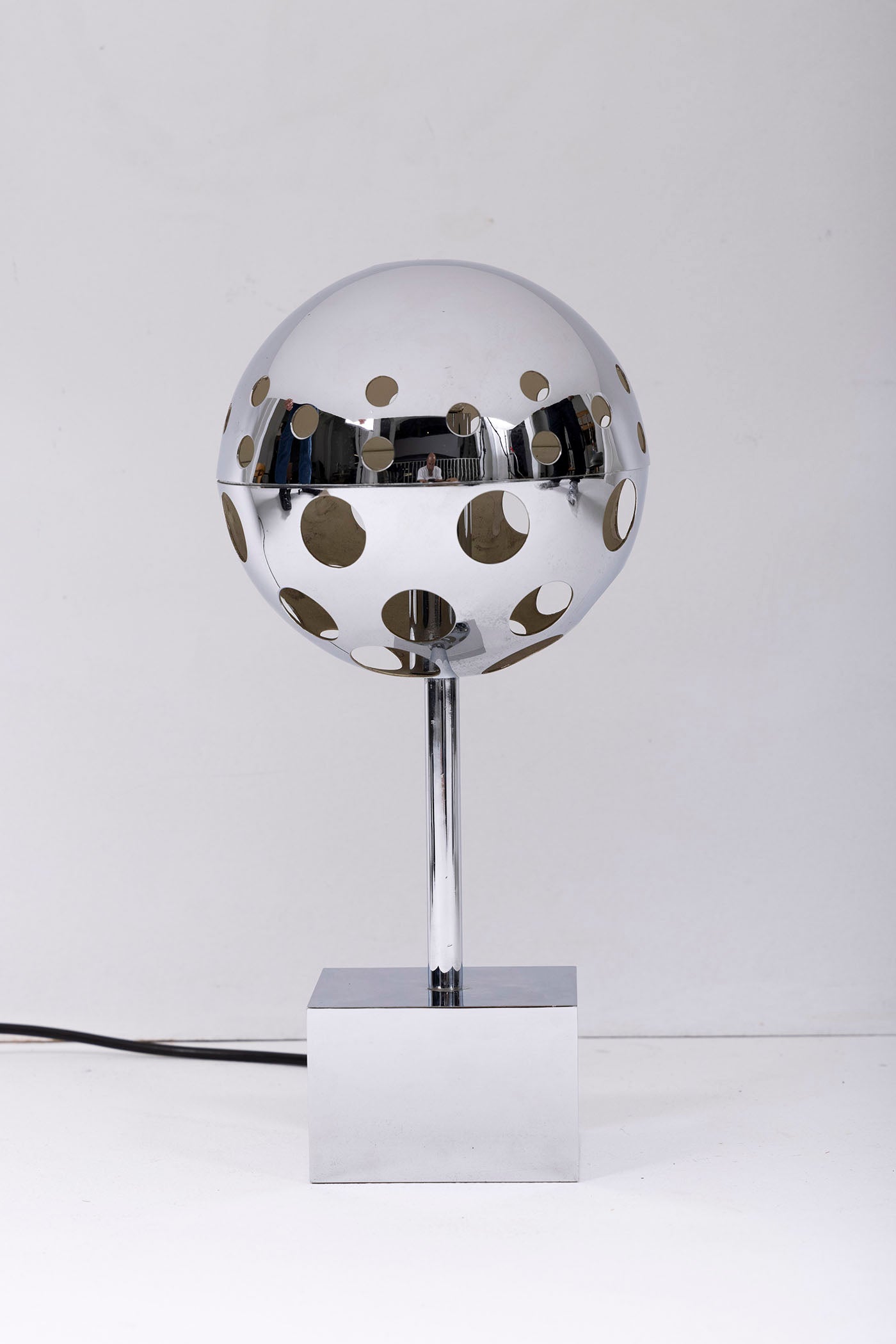 Lampe 10367 du designer Sabine Charoy éditée par Verre Lumière, années 1970. Lampe de table en métal chromé, avec une sphère ajourée sur une base cubique. Fonctionnelle et en très bon état. 