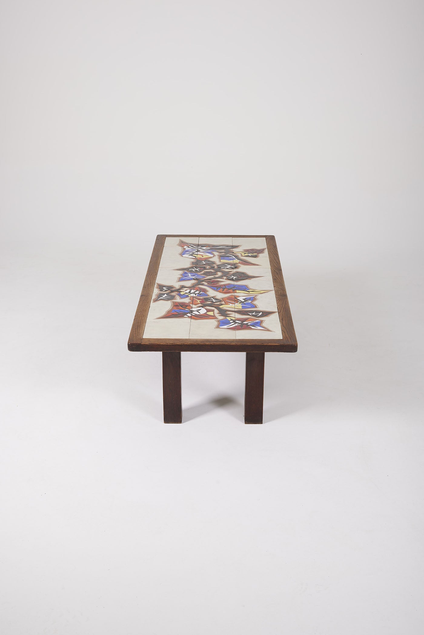 Table basse en céramique du céramiste français Jean Lurçat (1892-1966) datant des années 50. Le plateau est en céramique blanche à motif floraux jaune, rouge et bleu, la structure est en bois. Très bon état.