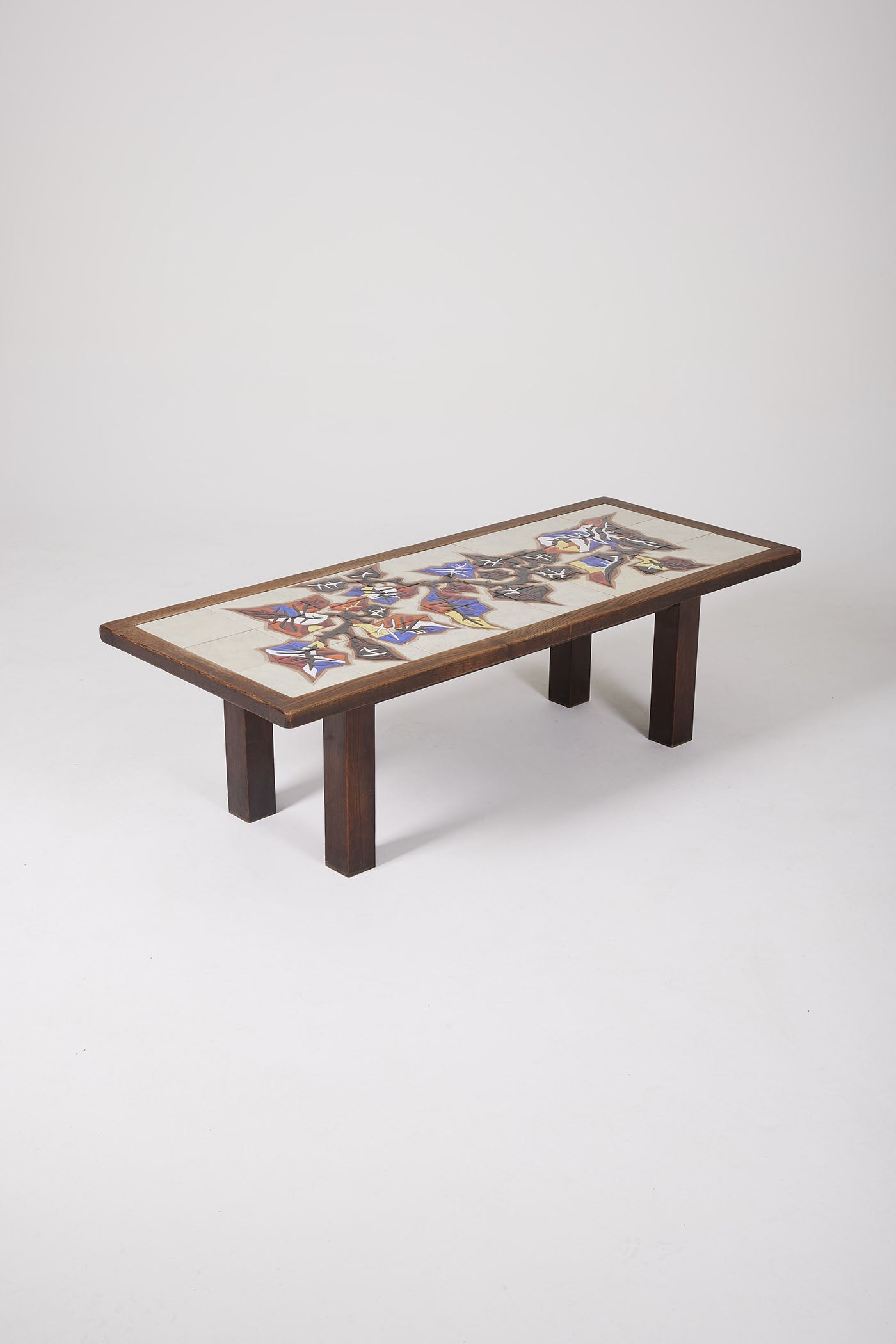 Table basse en céramique du céramiste français Jean Lurçat (1892-1966) datant des années 50. Le plateau est en céramique blanche à motif floraux jaune, rouge et bleu, la structure est en bois. Très bon état.