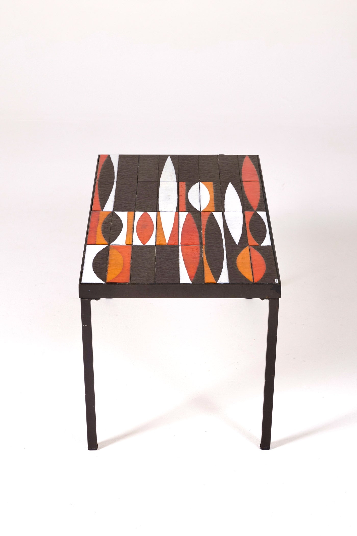 Table basse en céramique modèle Navette du céramiste Roger Capron, années 1960. La structure est en métal laqué noir et le plateau en céramique émaillée rouge, noir et blanc. Table signée R. Capron sur le coin. En parfait état. 