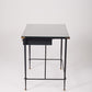  Bureau d'exception du designer Jacques Adnet (1900-1984), années 1940. Le piétement est en fer forgé patiné noir, le plateau en verre et les détails du bureau sont en cuir et laiton. Les deux tiroirs coulissants sont recouverts de cuir piqué à la main. Jacques Adnet a laissé une empreinte indélébile dans le monde du design avec son style distinctif et son innovation constante, il collabora notamment avec la maison Hermès sur des meubles en cuir de haute qualité, sa marque de fabrique.