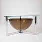 Table basse ou table d'appoint des années 1970. Elle est constituée d'un piètement en alu, d'un bac en plexiglas fumé et d'un plateau en verre. En bon état.