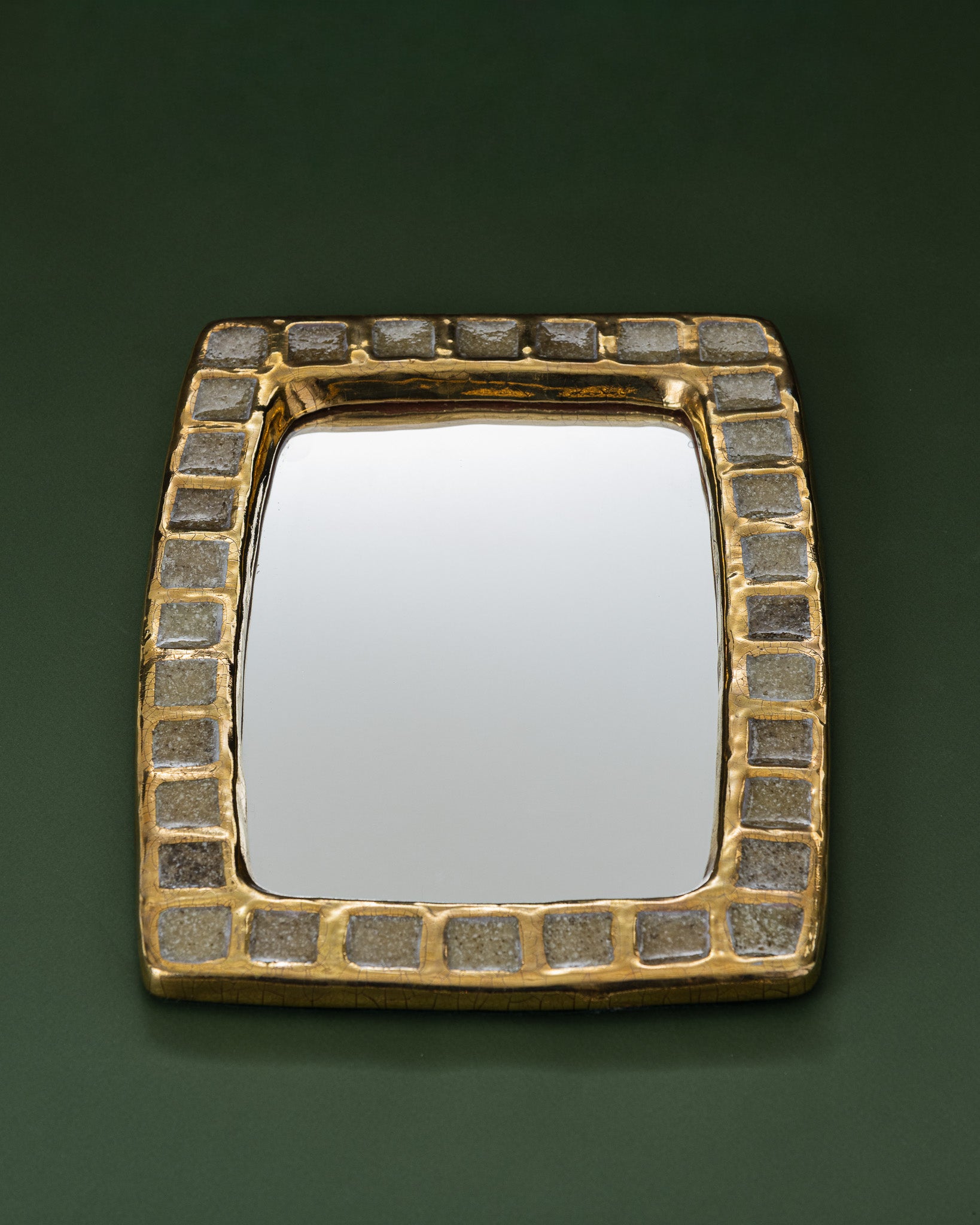 Miroir mural modèle "Pâte de verre long", conçu par Mithé Espelt dans les années 1950. Bordure en céramique estampée émaillée, incrustée de carrés de pâte de verre sur fond doré craquelé, caractéristique de ce modèle de collection répertorié dans la monographie d'Antoine Candau.