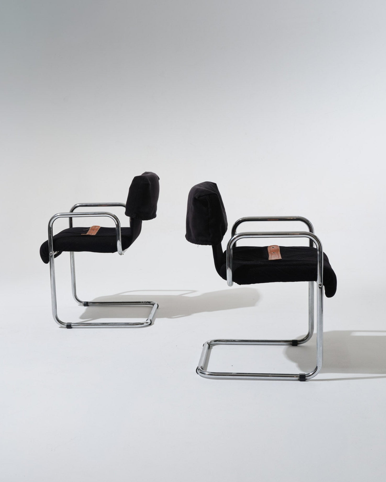 Paire de chaises de Guido Faleschini pour Mariani dans les années 1970. Structure en acier tubulaire chromé, assise et dossier généreusement rembourrés et recouverts d'un velours noir profond. Une sangle en cuir cognac, fixée par oeillets métalliques, souligne la ligne du siège.