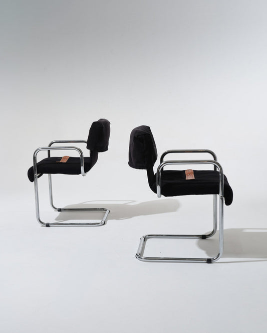 Paire de chaises de Guido Faleschini pour Mariani dans les années 1970. Structure en acier tubulaire chromé, assise et dossier généreusement rembourrés et recouverts d'un velours noir profond. Une sangle en cuir cognac, fixée par oeillets métalliques, souligne la ligne du siège.