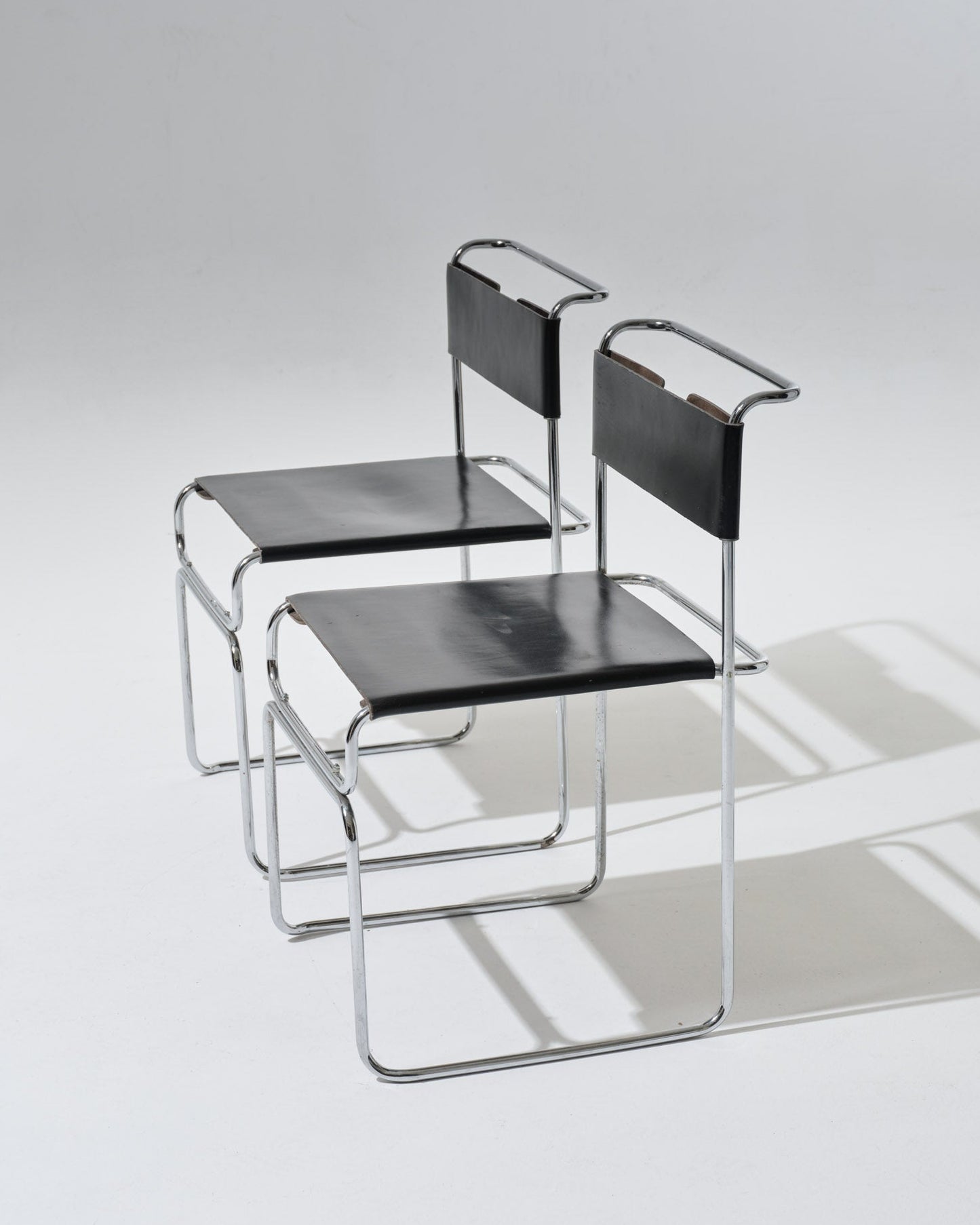 Paire de chaises Libellula dessinées par Giovanni Carini pour Tisettanta. Structure en acier tubulaire chromé, assise et dossier en cuir noir tendu, maintenus par un système de ressorts métalliques apparent à l'arrière.
Bon état général, à noter de légères marques visibles (voir photos).