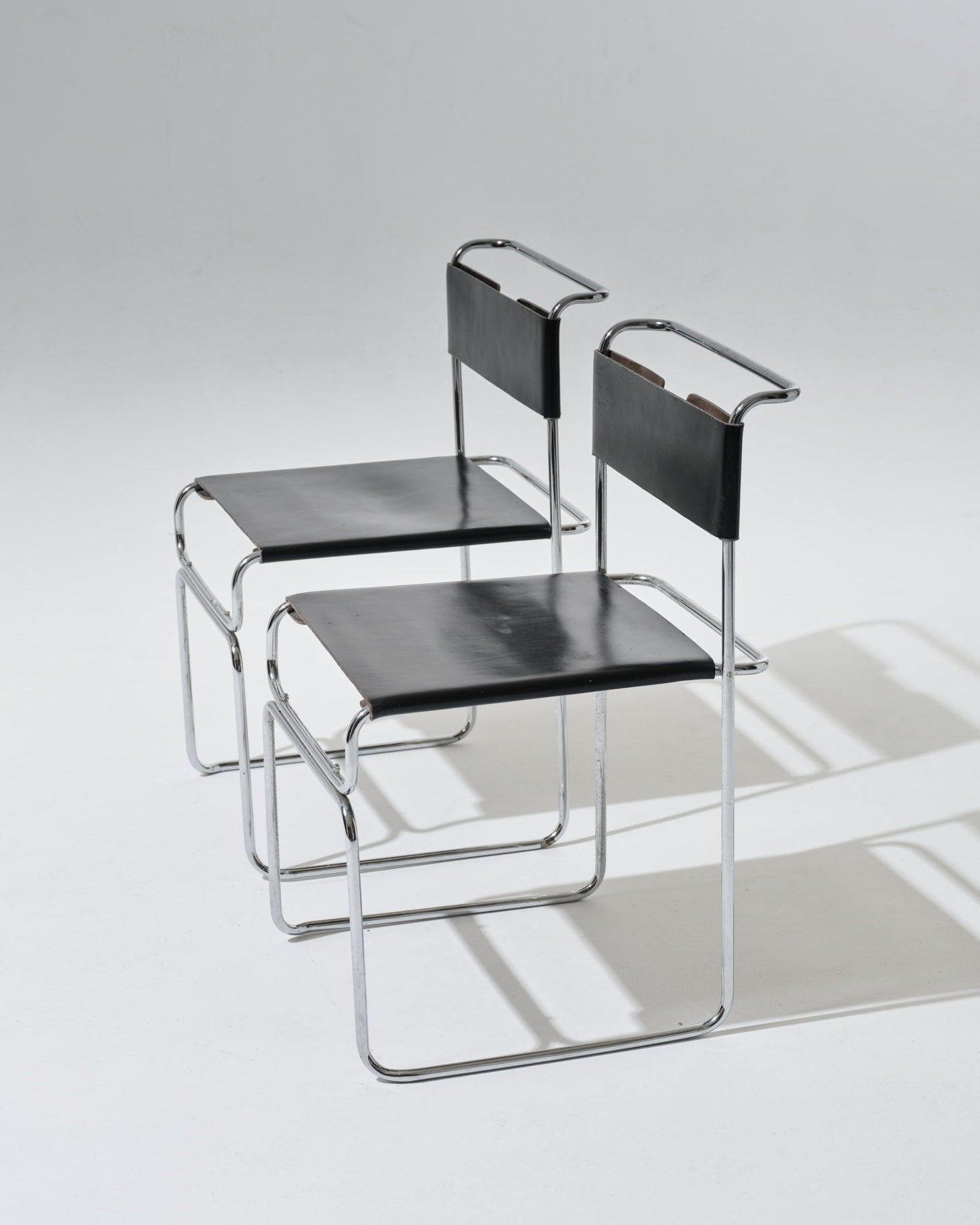 Paire de chaises Libellula dessinées par Giovanni Carini pour Tisettanta. Structure en acier tubulaire chromé, assise et dossier en cuir noir tendu, maintenus par un système de ressorts métalliques apparent à l'arrière.
Bon état général, à noter de légères marques visibles (voir photos).