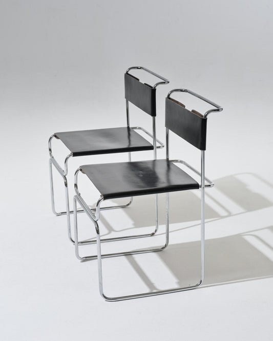 Paire de chaises Libellula dessinées par Giovanni Carini pour Tisettanta. Structure en acier tubulaire chromé, assise et dossier en cuir noir tendu, maintenus par un système de ressorts métalliques apparent à l'arrière.
Bon état général, à noter de légères marques visibles (voir photos).