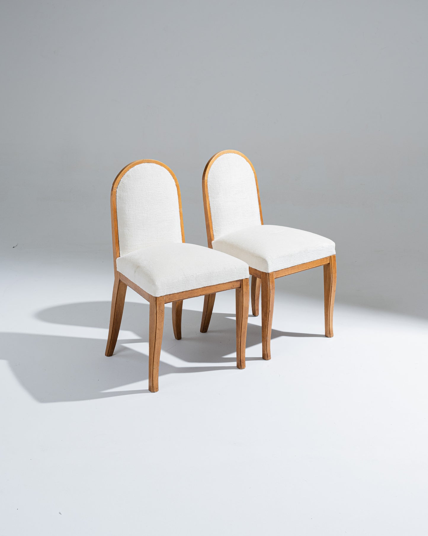 Paire de chaises René Prou, réalisées dans les années 1940. Structure en bois clair aux lignes galbées typiques du style néo-classique moderne de l'époque, dossier cintré et assise recouverte d'un tissu écru texturé.
Parfait état.