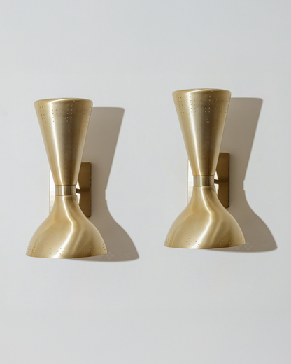 Paire d’appliques murales en laiton brossé, dites “Diabolo”, typiques du design italien des années 1960. Chaque applique présente un double abat-jour orientable, perforé sur les bords pour diffuser une lumière douce et ponctuelle. Très bel état.