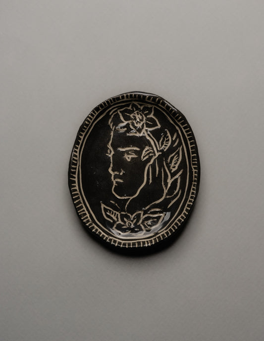 Petit vide-poche ovale en céramique émaillée noire, décor gravé d'un profil masculin orné de fleurs. Bordure finement striée à la main. Signature en creux ELDAROV. T au revers. Parfait état.