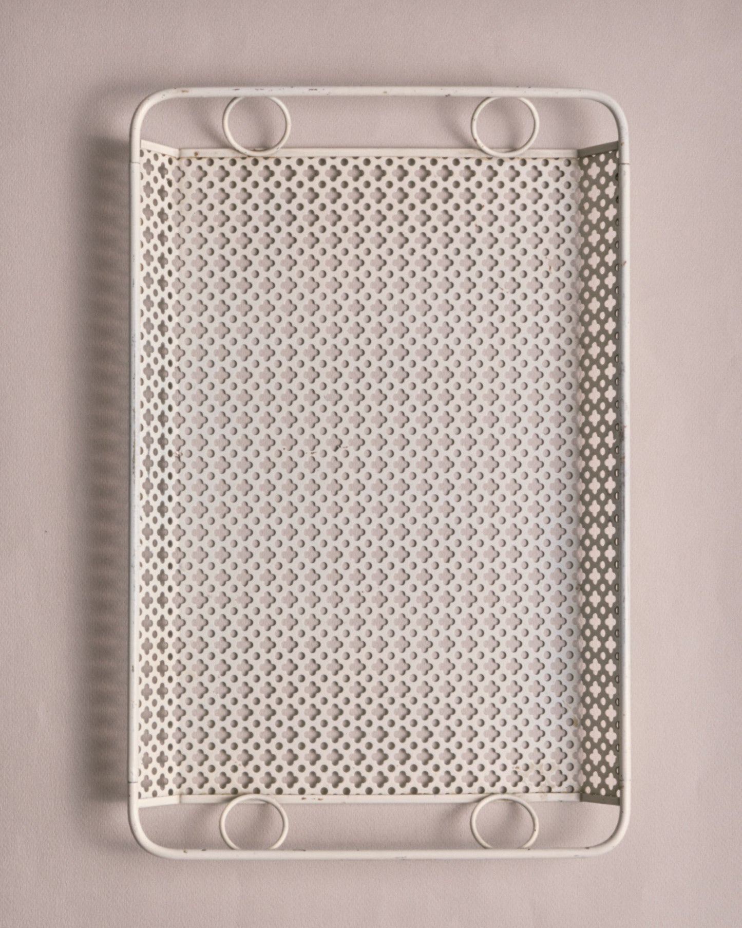 Plateau rectangulaire en métal laqué blanc, à décor ajouré de petits motifs trèfles, bordé d'un cadre tubulaire et poignées circulaires. Travail de Mathieu Matégot, figure emblématique du design français des années 1950. Bel état vintage.&nbsp;