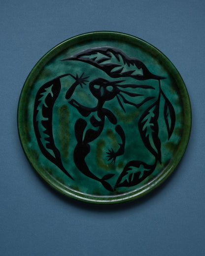 Plat rond en céramique émaillé, signé Jean Lurçat (1892-1966) pour l'atelier Sant-Vicens dans les années 1950. Décor central typique de l'artiste, représentant une figure stylisée entourée d'éléments végétaux et organiques, noir sur fond émaillé vert nuancé. Contours gravés et émail craquelé d'origine.&nbsp;
Pièce numérotée 45/50, portant la signature manuscrite "J. Lurçat - Sant Vicens". Parfait état.
