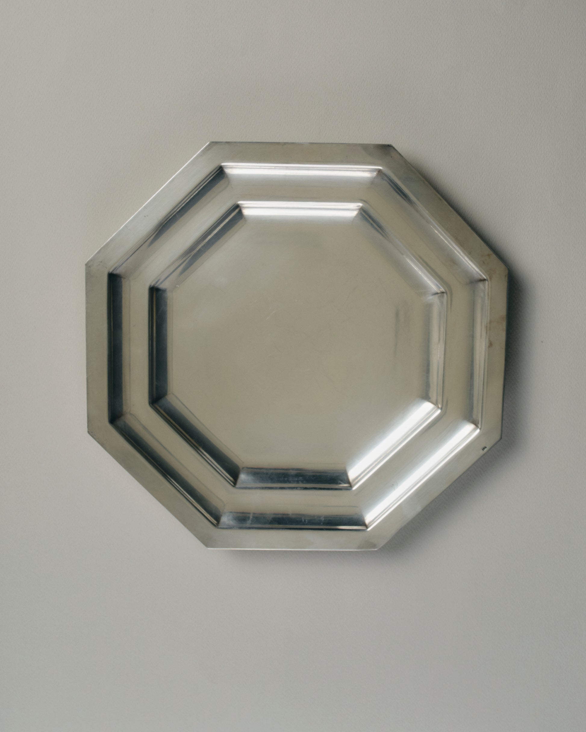 Plat octogonal en métal argenté des années 1950. Travail européen. Forme géométrique à double gradin, typique des arts de la table de l'après-guerre. Pouvant service de plat de service, vide-poche ou plateau décoratif sur une table basse ou une enfilade.
Bon état général, quelques traces d'usage et patine conformes à l'âge.