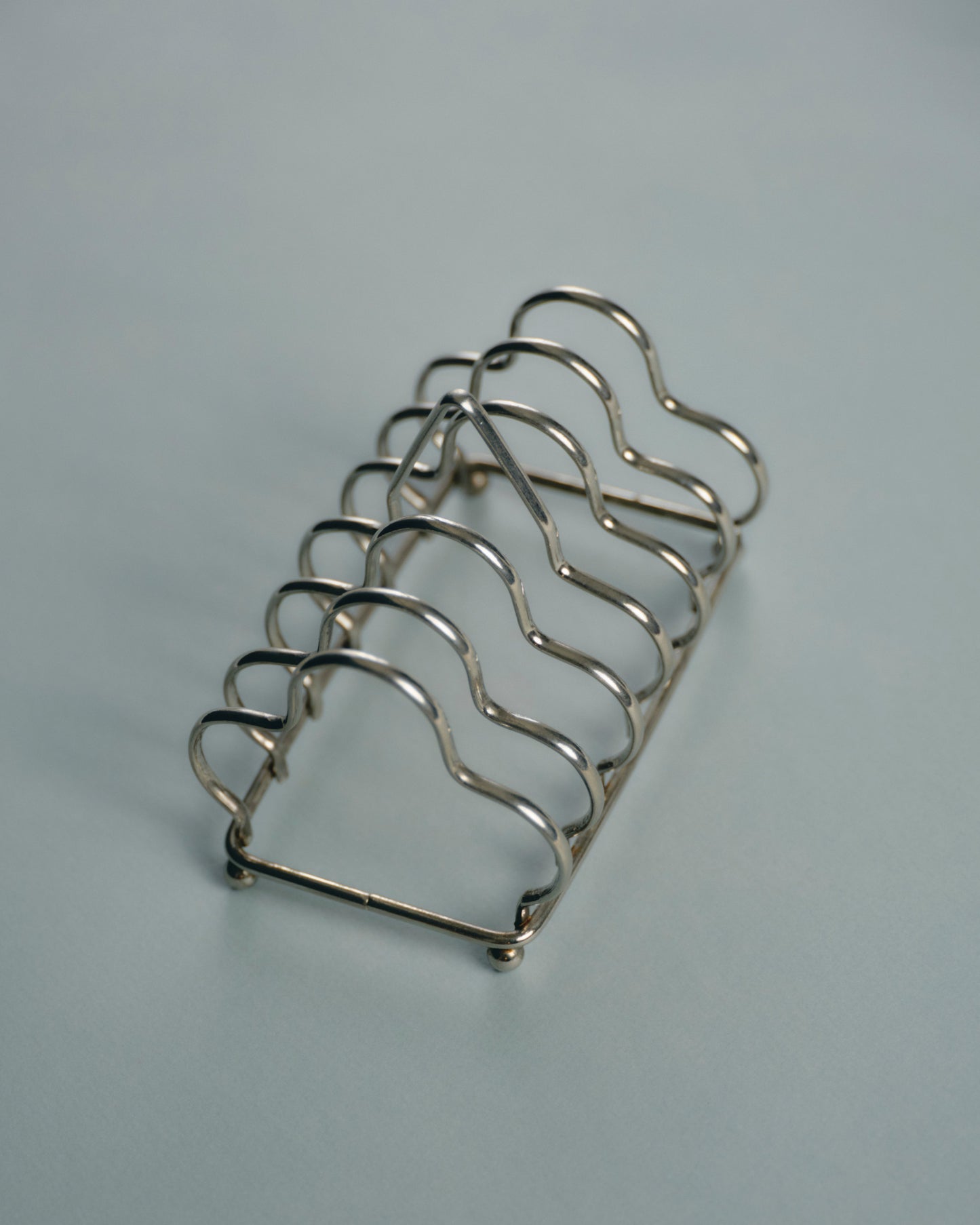 Porte-toasts en métal argenté, à structure filaire ondulée formant cinq compartiments. Bel état général, patine légère conforme à l'usage.