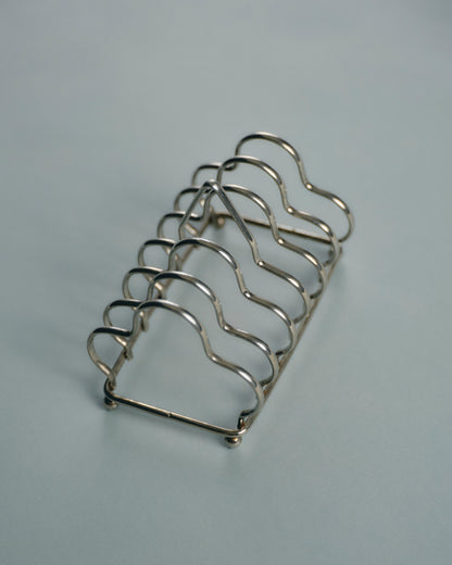 Porte-toasts en métal argenté, à structure filaire ondulée formant cinq compartiments. Bel état général, patine légère conforme à l'usage.