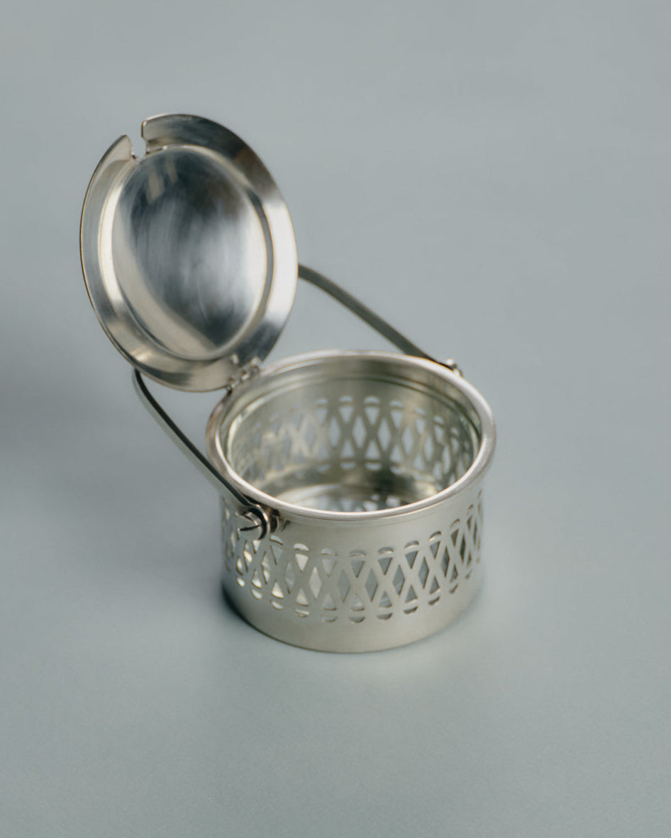 Pot de service à parmesan ou confiture en métal argenté et verre, travail français des années 1950. Monture ajourée à motif de croisillons, couvercle assorti et anse latérale fine. Le récipient intérieur est en verre épais transparent — également appelé verre-confiturier. Anse latérale fine et couvercle assorti.
Très bon état général, légères traces d’usage conformes à l’âge