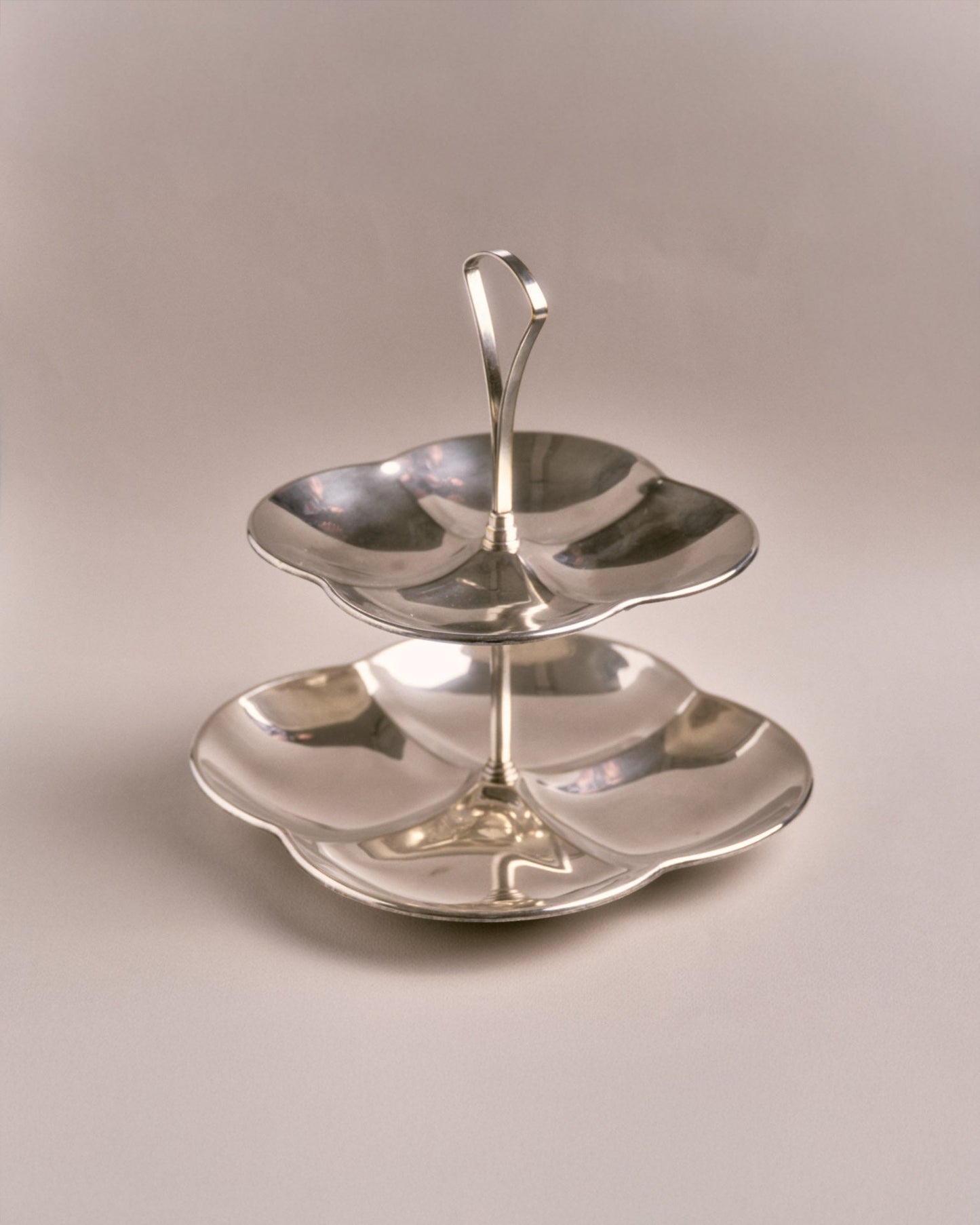 Présentoir à deux étages en métal argenté, réalisé dans les années 1960. Structure composée de deux plateaux à bords ondulés reliés par une tige centrale. Idéal pour présenter des apéritifs ou mignardises.
Très bon état, légère patine conforme à l'âge.