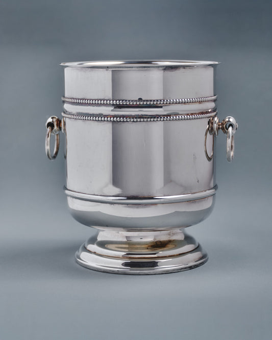 Seau à champagne de la maison Christofle, modèle "Perles" en métal argenté. De forme tulipe sur piédouche à décor de frises de perles et prises à anneaux mobiles. Signé et poinçon de maître.