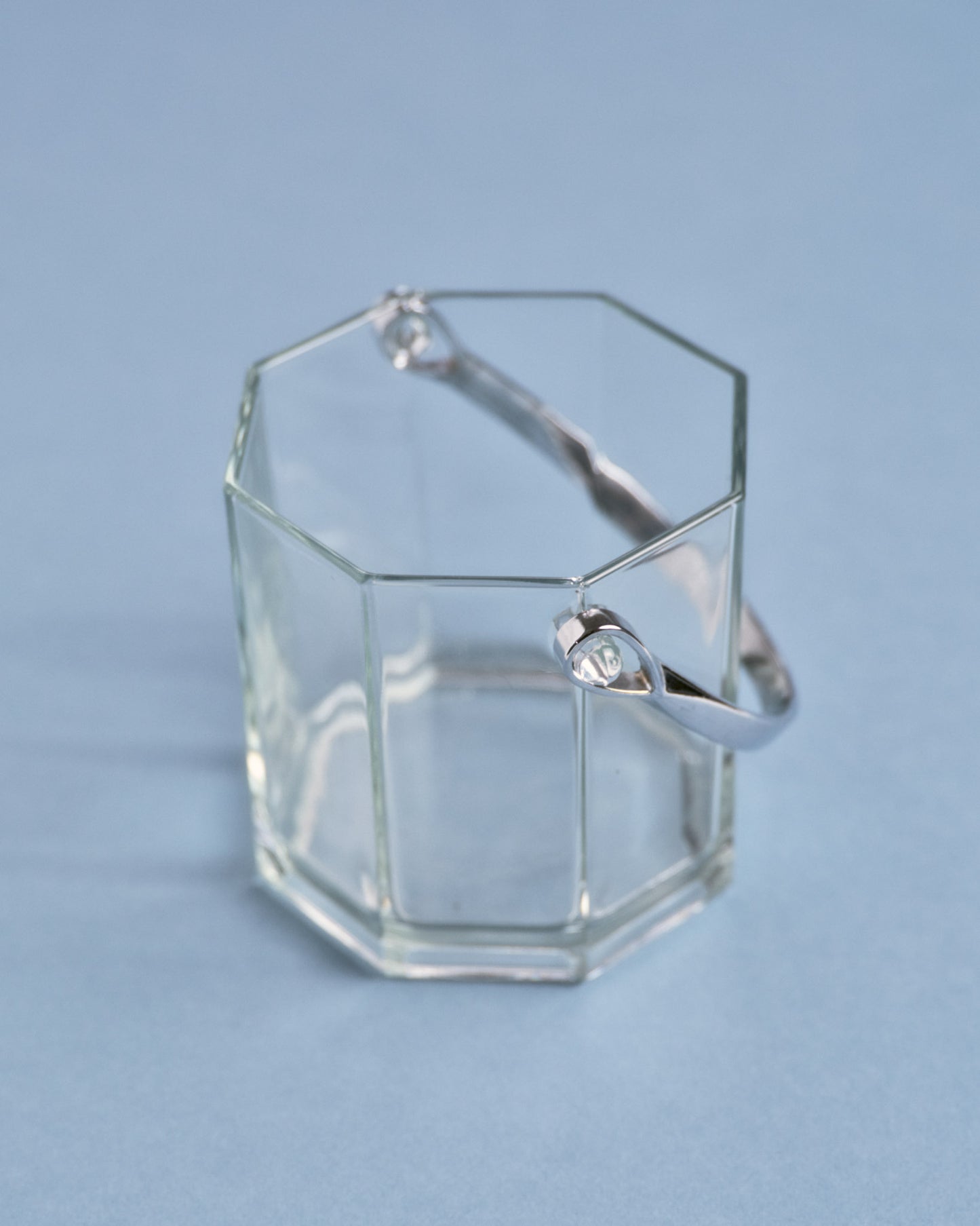 Seau à glace en verre à panse géométrique facettée, muni d'une anse en métal chromé. Un modèle typique du design années 1970.