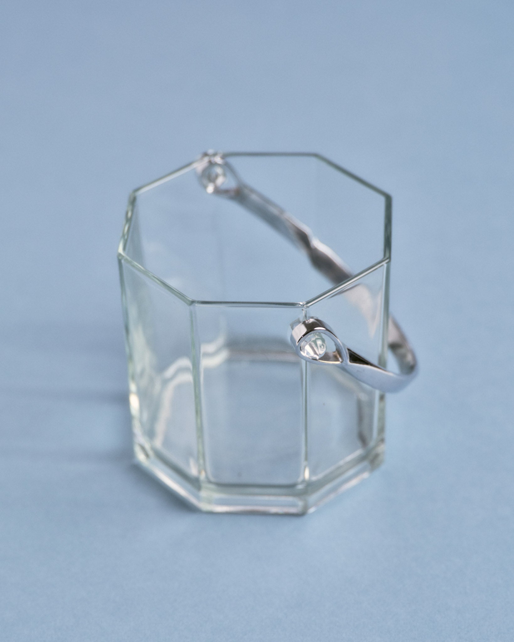 Seau à glace en verre à panse géométrique facettée, muni d'une anse en métal chromé. Un modèle typique du design années 1970.