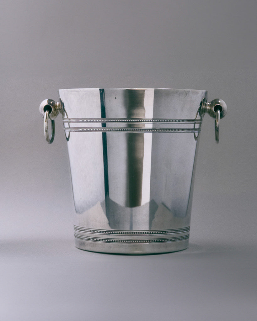 Seau à champagne en métal argenté. Modèle à décor de filets perlés et anses à anneaux, typique des productions des années 1950. Bel état général, légère patine conforme à l'âge.