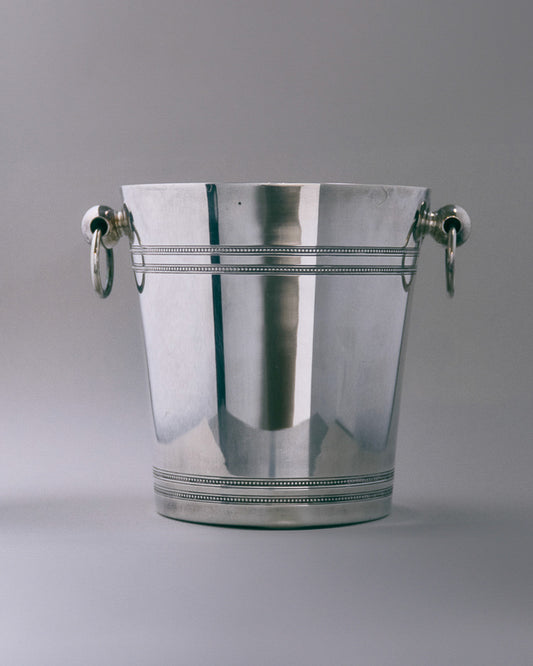 Seau à champagne en métal argenté. Modèle à décor de filets perlés et anses à anneaux, typique des productions des années 1950. Bel état général, légère patine conforme à l'âge.