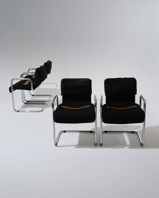 Set de 4 chaises de Guido Faleschini pour Mariani dans les années 1970. Structure en acier tubulaire chromé, assise et dossier généreusement rembourrés et recouverts d'un velours noir profond. Une sangle en cuir cognac, fixée par oeillets métalliques, souligne la ligne du siège.