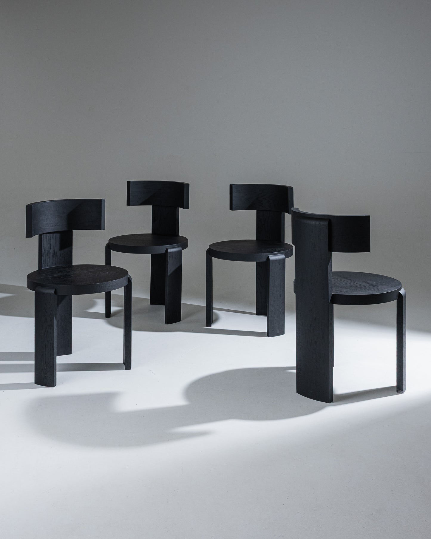 Set de 4 chaises "Spina" en chêne massif, finition teintée noir, par Louise Roe.&nbsp;
La collection Spina se caractérise par sa structure tripode et son assise circulaire. La pièce centrale, plus large, évoque la colonne vertébrale (spina en latin) et rappelle l’importance d’une posture droite.
Pensée pour la vie de tous les jours et en parfaite harmonie avec les tables "Pillabout", la chaise "Spina" arbore un arrière-dos cintré qui enveloppe l’usager et invite à la détente, alliant esthétique sculpturale 