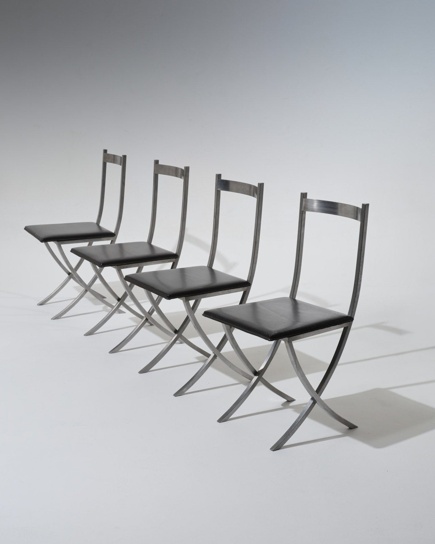 Set de 4 chaises par Xavier Feal, France, 1970s. Chaises au design géométrique typique du travail de Feal, réalisées en aluminium brossé avec assise en skaï noir. La structure en croix confère une silhouette légère et architecturale, emblématique du design français des années 1970.
Bel état, belle patine conforme à l'âge. À noter, l'une des chaises a une légère marque sur l'assise.