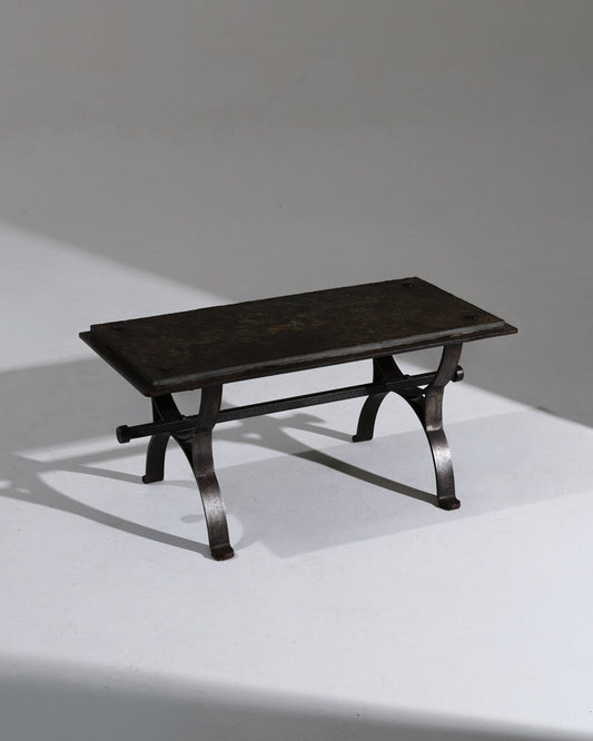 Table basse rectangulaire au piètement en fer forgé patiné, surmontée d'un plateau en ardoise naturelle aux nuances profondes. Les détails rivetés et la structure galbée confèrent à l'ensemble un caractère artisanal, typique du travail du fer français des années 1950. Très bel état.