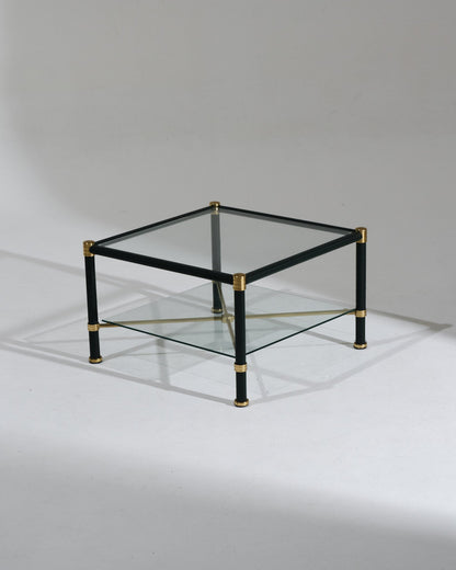 Table basse carrée dans le goût de Jacques Adnet. Travail des années 1950. Structure en laiton gainée de cuir vert foncé à couture sellier, double plateau en verre clair et croisillons centraux en laiton. Parfait état.&nbsp;