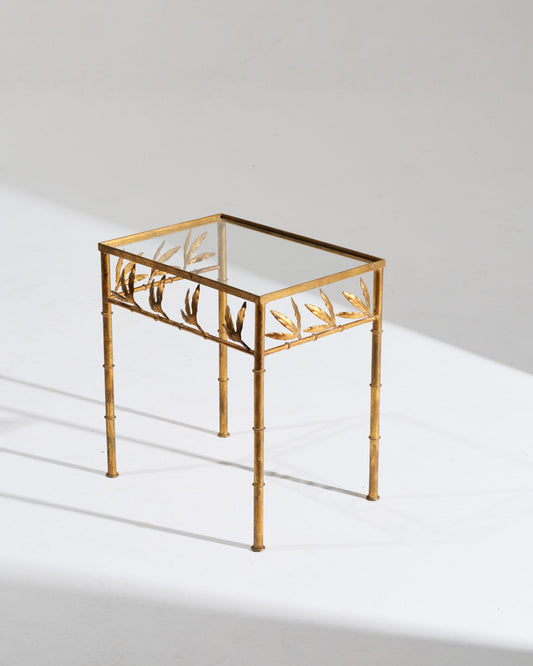Table d'appoint en laiton doré, au décor de tiges et de feuillages, typique des créations italiennes des années 1970. Les plateaux en verre clair laissent apparaître le travail ornemental de la structure, inspirée du bambou. Très bon état vintage.&nbsp;