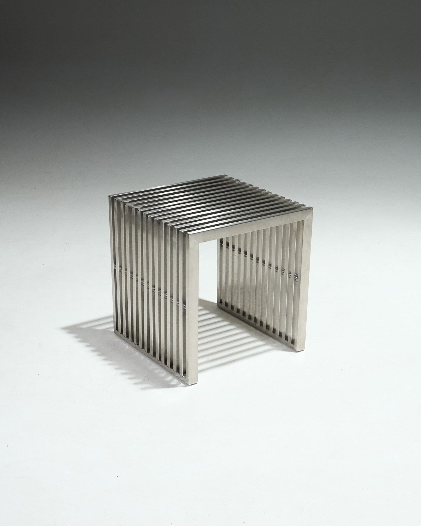 Tabouret moderniste en inox brossé, avec structure ajourée composée de lames verticales.&nbsp;Pièce dans l’esthétique minimaliste des années 1980, influencée par le design Bauhaus, mettant en avant des formes épurées et l’usage de matériaux industriels.&nbsp;