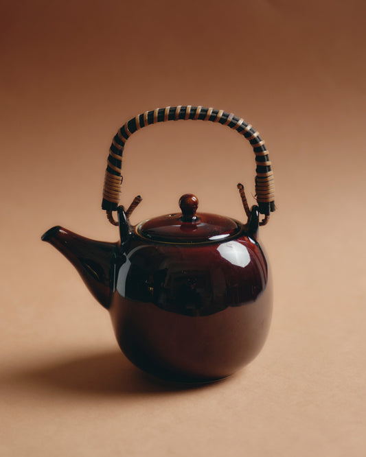 Théière japonaise en céramique émaillée brun profond, anse en rotin tressé bicolore. Design sobre et harmonieux, typique des productions japonaises de la fin du XXe siècle. Parfait état.