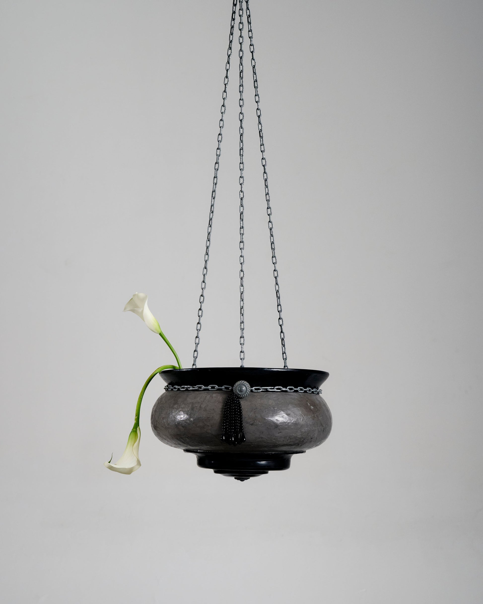 Suspension Le Brasero en forme de vasque réalisée par l'artiste Jordan Joevin. Structure en béton et bitume, suspendue par trois chaînes métalliques. Signature visible dans la vasque.