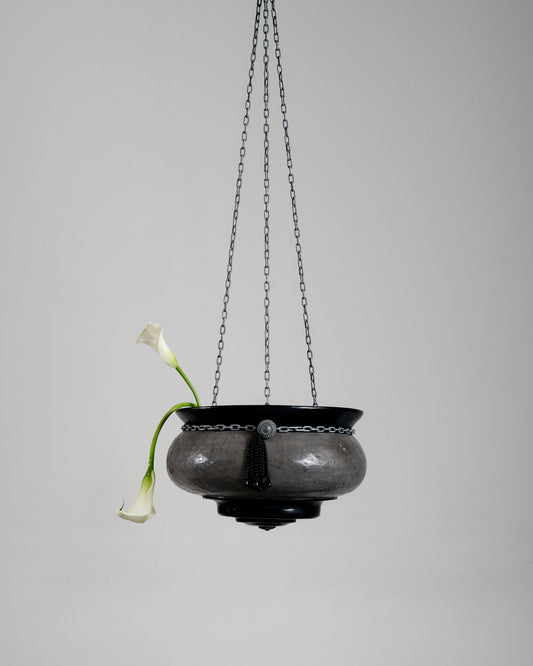 Suspension Le Brasero en forme de vasque réalisée par l'artiste Jordan Joevin. Structure en béton et bitume, suspendue par trois chaînes métalliques. Signature visible dans la vasque.