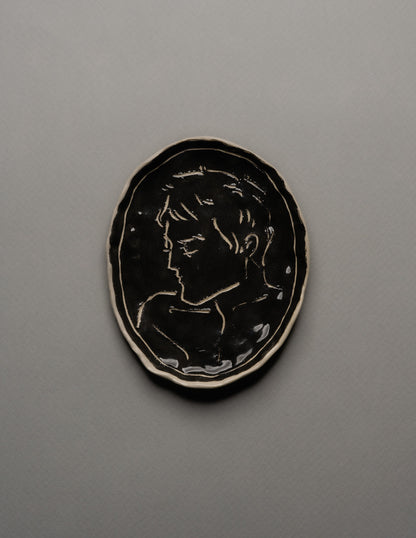 Vide-poche ovale en céramique émaillée noire, décor incisé d'un profil masculin stylisé sur fond brillant. Bord irrégulier souligné d'un fin filet blanc. Pièce unique signée « Eldarov. T » au revers. Parfait état.