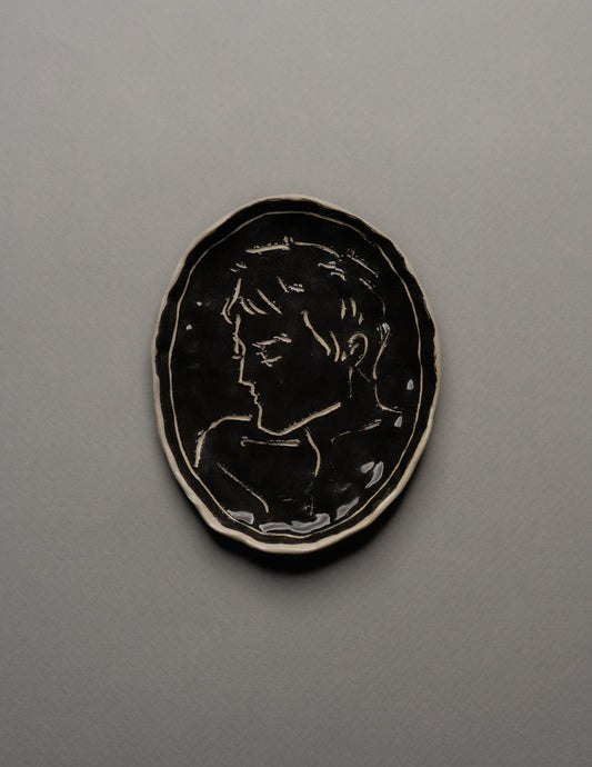 Vide-poche ovale en céramique émaillée noire, décor incisé d'un profil masculin stylisé sur fond brillant. Bord irrégulier souligné d'un fin filet blanc. Pièce unique signée « Eldarov. T » au revers. Parfait état.